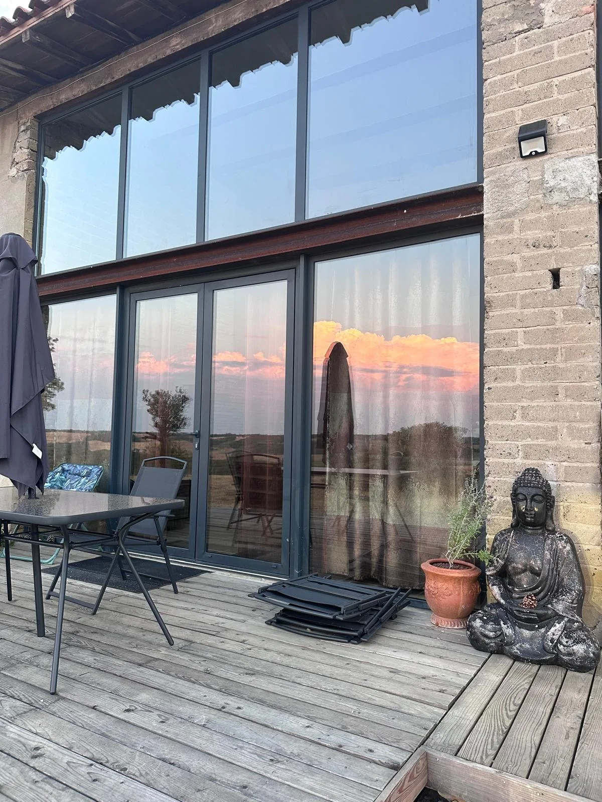 Terrasse en bois devant la grande façade vitrée du gîte