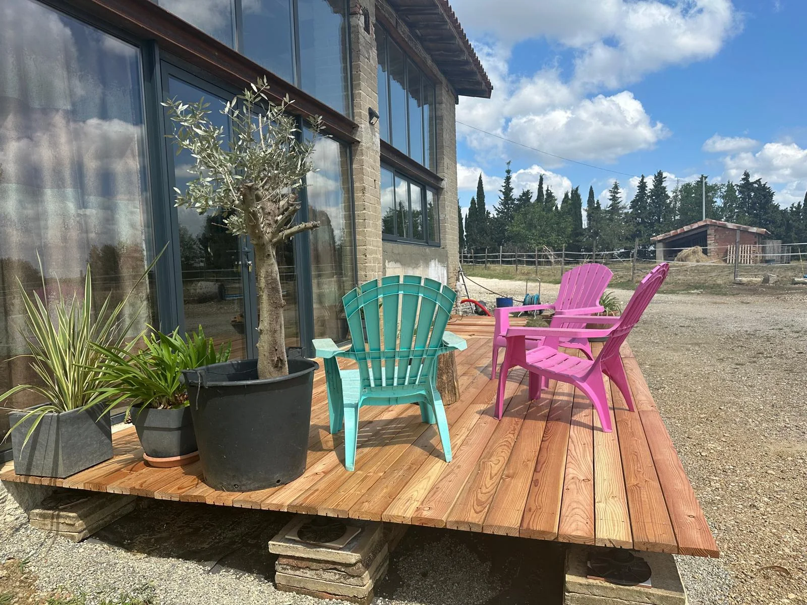 Petite terrasse en bois avec fauteuils colorés devant la façade vitrée